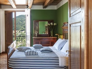 A bedroom with a bed, dresser, and a view of a green landscape. - Belvilla by OYO Villa Costiera (Vibonati)