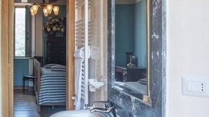 A bathroom with a large mirror, a sink, and a shower area.