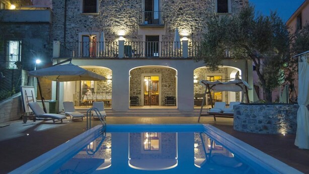 A stone building with a pool and outdoor seating.