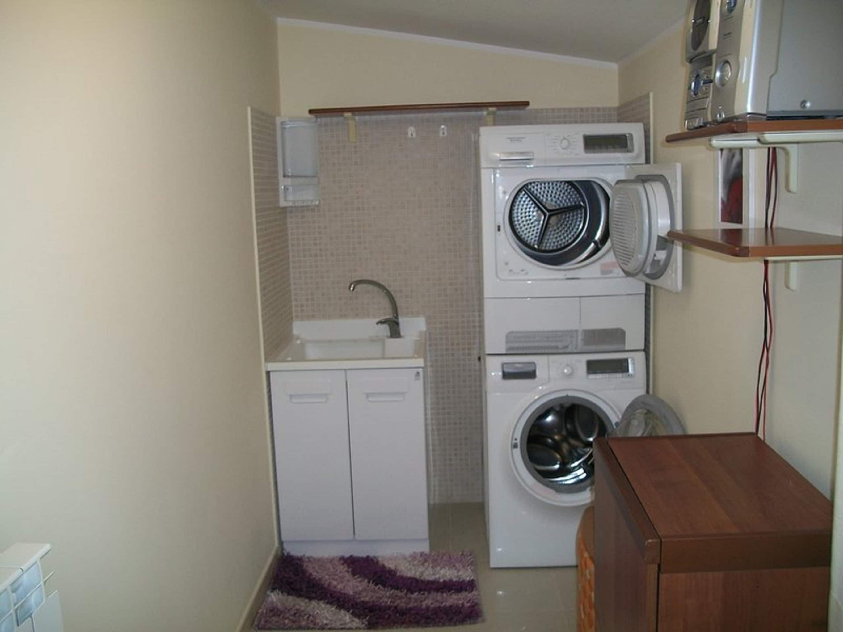 Une petite buanderie équipée d’un lave-linge, d’un sèche-linge et d’un petit évier.
