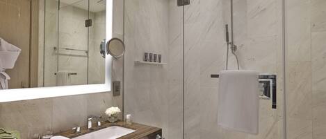 A modern bathroom with a glass-enclosed shower, a wooden vanity with a sink, and a large mirror.