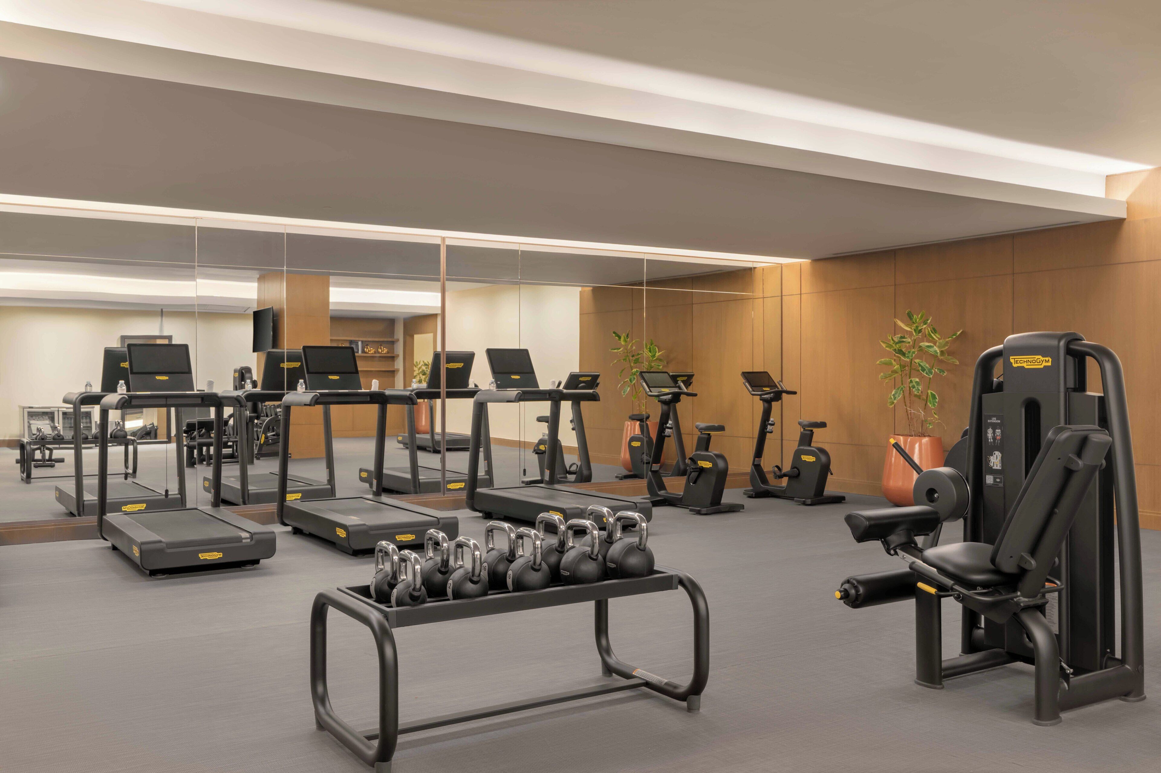 A gym with treadmills, elliptical machines, and free weights.