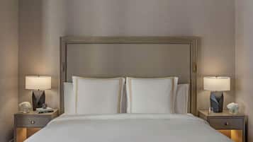 Una cama bien hecha con sábanas blancas, dos mesitas de noche con lámparas y un cabecero grande.