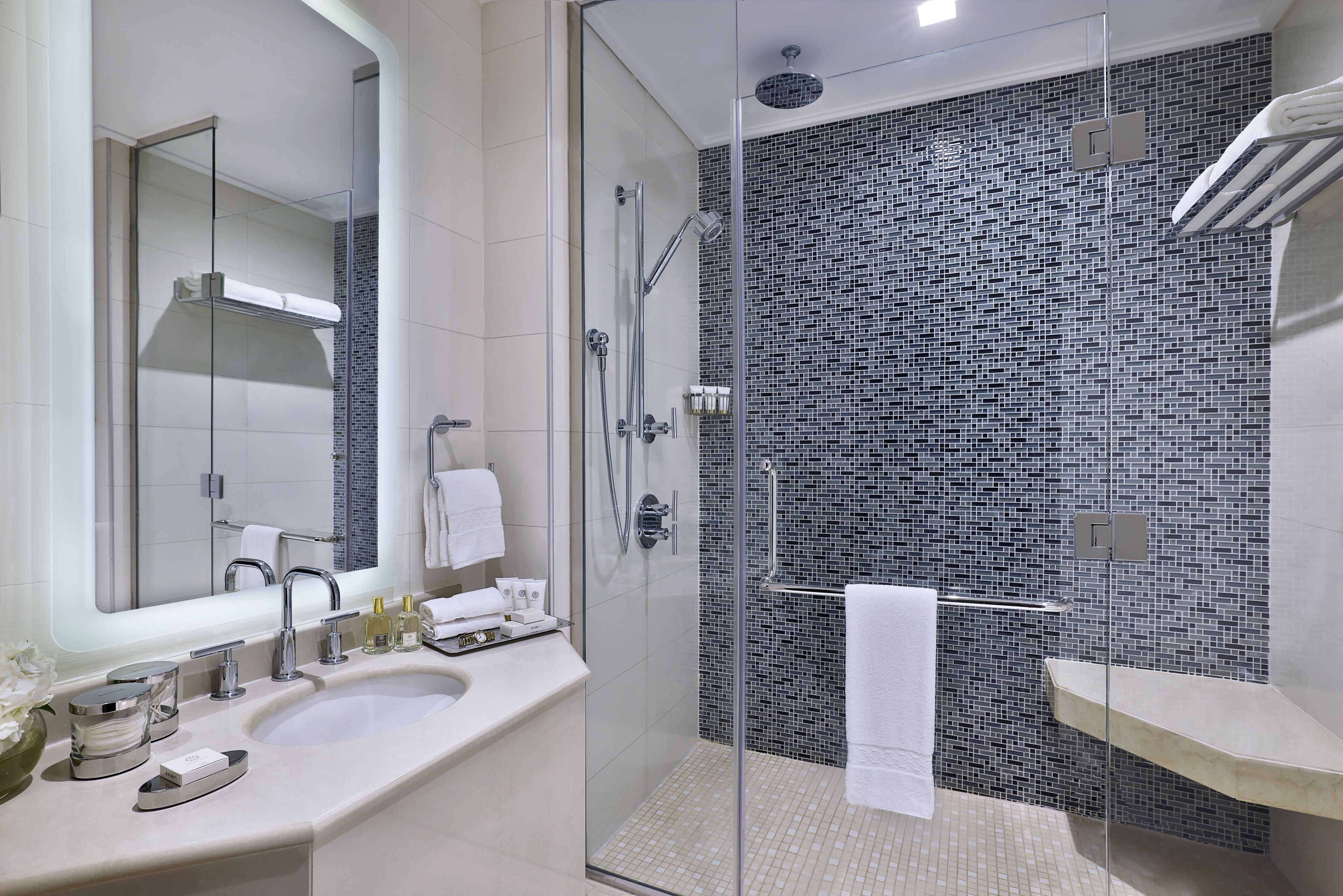 Un baño moderno con ducha acristalada, un espejo grande y un lavamanos blanco.