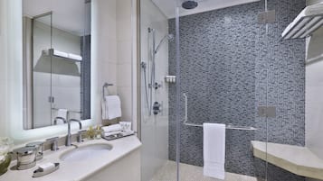A modern bathroom with a glass-enclosed shower, a large mirror, and a white sink.