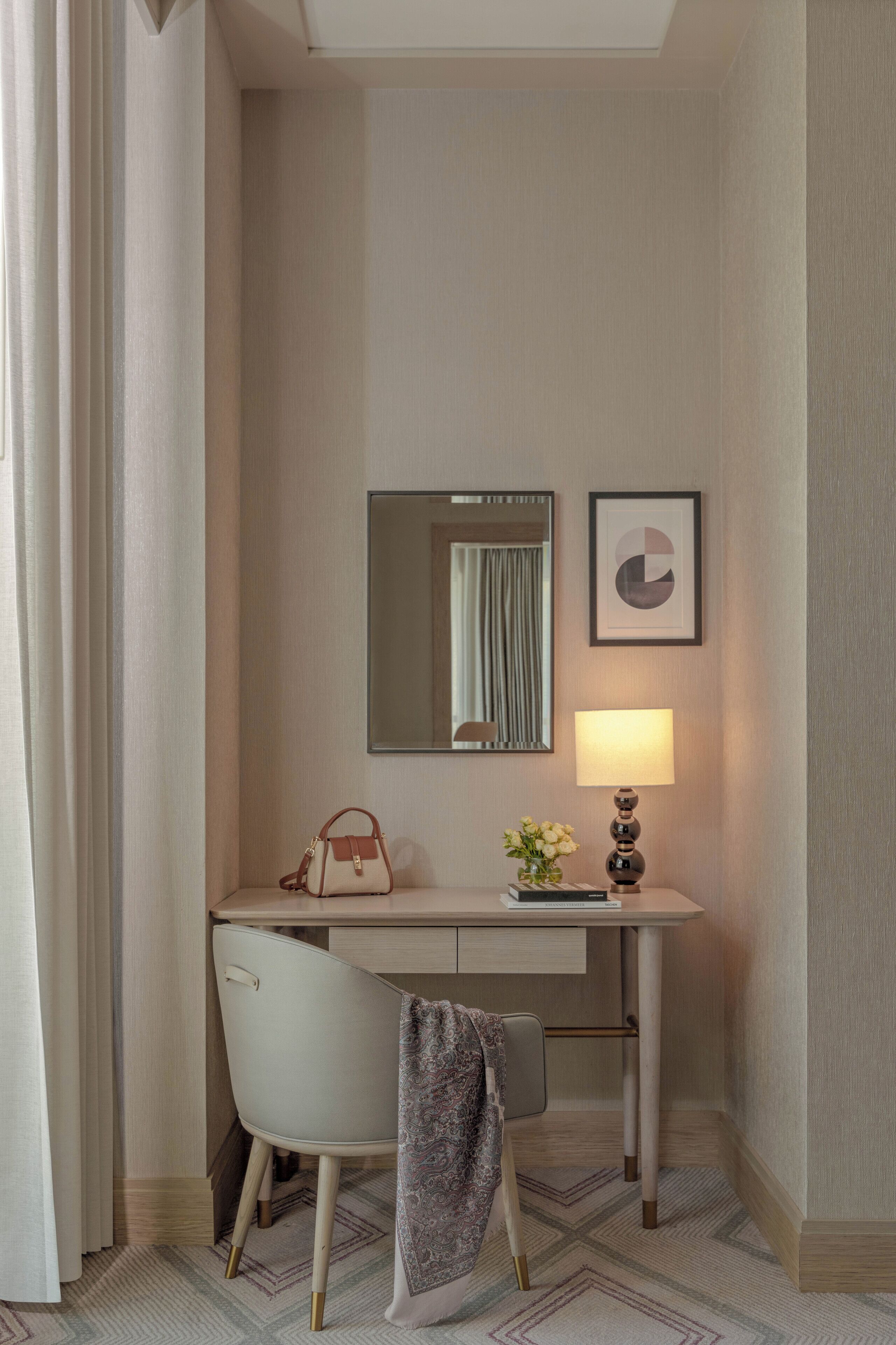 Et hotelværelse med skrivebord, stol, lampe og et spejl.