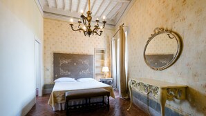 Un dormitorio con cama, mesita de noche, cómoda, espejo y candelabro.