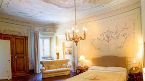 Una habitación lujosa con una cama grande, una araña y elaborados detalles artísticos en el techo.