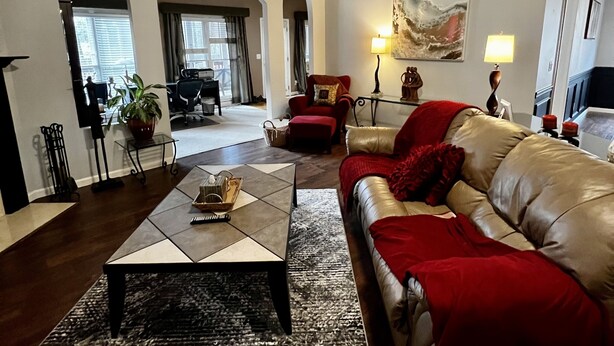 A spacious living room with a large sofa, a coffee table, and a fireplace. There are arched doorways and a large window. - Perfect luxury home, close to social settings but far enough for peace. (Acworth)