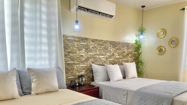 Habitación de hotel con dos camas, una pared de acento de piedra, una planta en maceta y un reloj de pared.