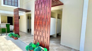 Un edificio moderno con un patio empedrado, plantas en macetas y una separación de madera.