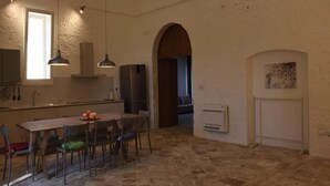 A kitchen with a dining table and chairs, a refrigerator, and pendant lights. - Villa Near Lecce With Garden and Beaches (Monteroni di Lecce)