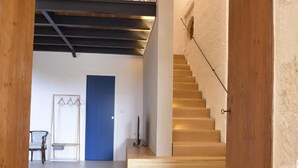 A modern interior with a wooden staircase, a blue door, and a chair in the background. - Villa Near Lecce With Garden and Beaches (Monteroni di Lecce)