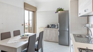Una cocina moderna con comedor, que incluye un refrigerador de acero inoxidable, microondas y estufa a gas.
