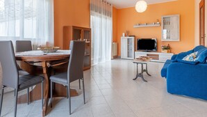 Una sala de estar moderna con comedor, que incluye un televisor, sofá y mesa de comedor con sillas.