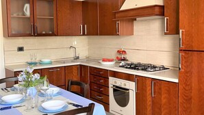 Uma cozinha moderna com armários de madeira, fogão a gás, forno e área de jantar posta com pratos e copos.