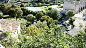 Eine Villa mit Swimmingpool, Steinbauten und einem angelegten Garten.