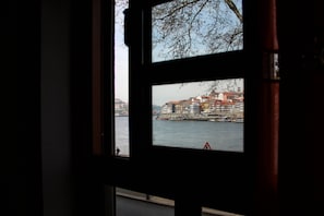 Vista a través de una ventana que muestra un paisaje urbano costero, con edificios y una masa de agua.