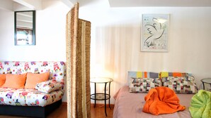 A cozy bedroom with a bed, a sofa, and a small table. - Estúdio vista rio Douro (Vila Nova de Gaia)
