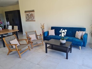 A living room with a blue sofa, two wicker chairs, a coffee table, and a world map on the wall.