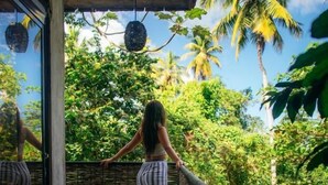 A balcony with a view of lush greenery and palm trees. - Taino Beach Lofts (Samaná)