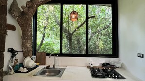A kitchen with a large window, wooden cabinets, a sink, and a stove. - Taino Beach Lofts (Samaná)