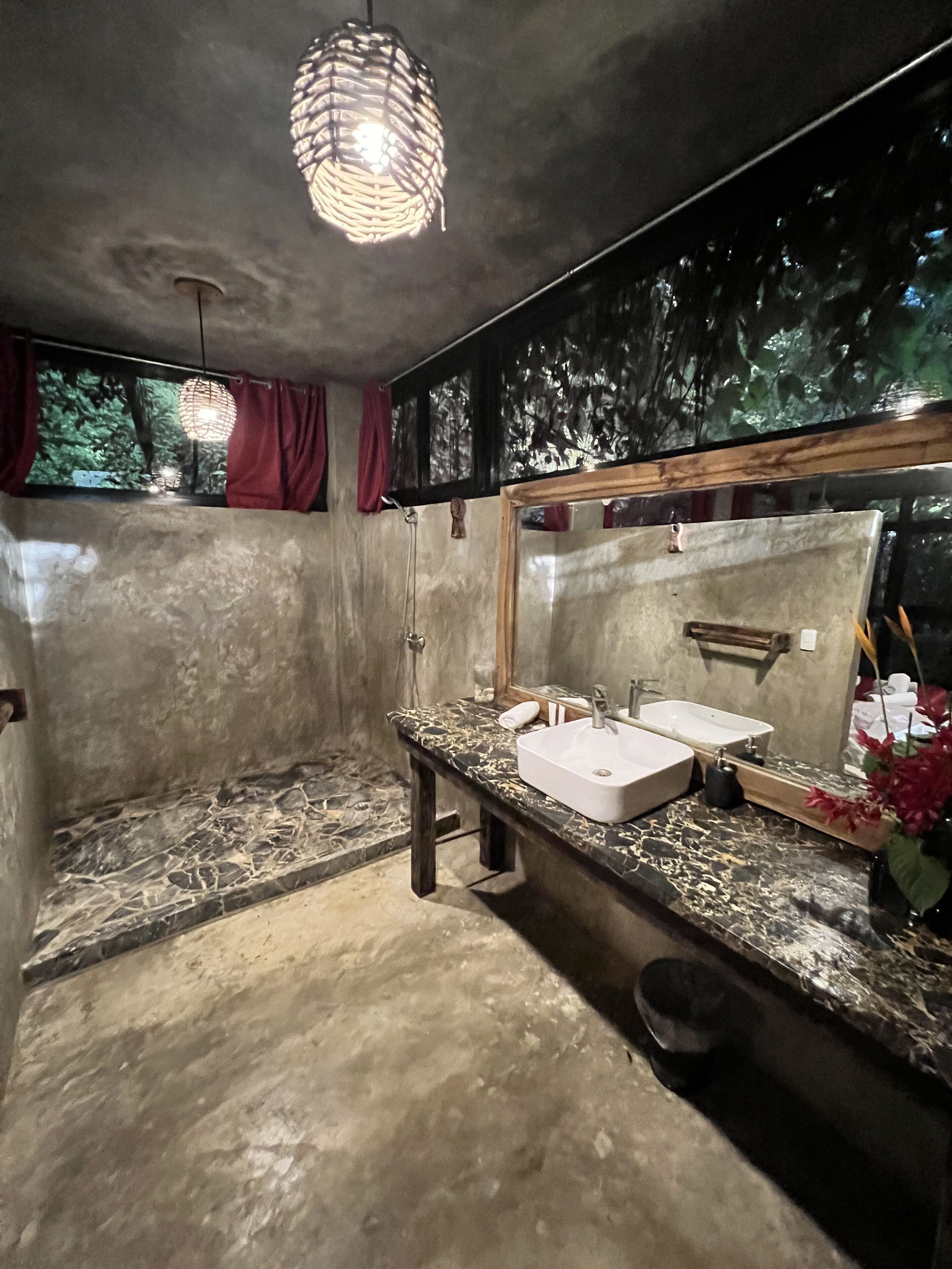 A bathroom with a marble countertop, two sinks, a large mirror, and a hanging light fixture.