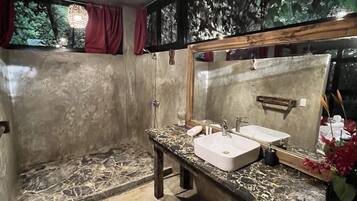A bathroom with a marble countertop, two sinks, a large mirror, and a hanging light fixture.