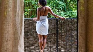 A person standing in a room with a view of a lush green garden through a window. - Taino Beach Lofts (Samaná)