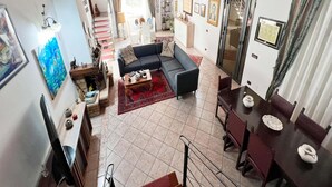 A spacious living area with a sofa, coffee table, and dining table. A staircase leads to an upper level. - Villa, Castellammare del Golfo (Castellammare del Golfo)