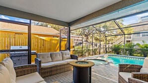 A covered outdoor patio with wicker furniture, a barbecue grill, and a swimming pool. - Heated Saltwater Pool & Spa l Family Friendly l Near Beaches & Clearwater (Palm Harbor)