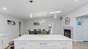 A modern kitchen with white cabinetry, pendant lighting, and a marble island. - Heated Saltwater Pool & Spa l Family Friendly l Near Beaches & Clearwater (Palm Harbor)
