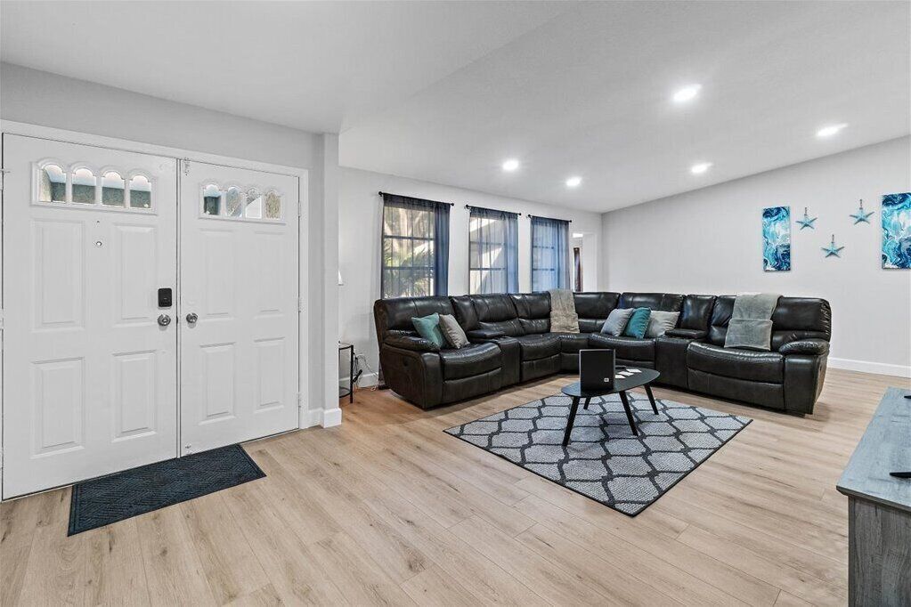 A modern living room with a sectional sofa, a coffee table, and a large window with curtains.