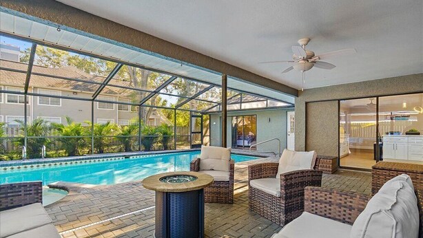 A covered outdoor pool area with wicker furniture and a ceiling fan. - Heated Saltwater Pool & Spa l Family Friendly l Near Beaches & Clearwater (Palm Harbor)