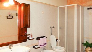 Un baño con lavamanos, dos inodoros, ducha y espejo.
