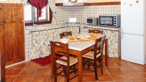Una cocina con una mesa de comedor, sillas, estufa, microondas y refrigerador.