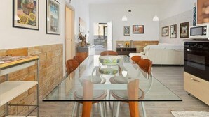 A modern kitchen with a glass dining table, wooden cabinets, and a microwave. - Alcamo Marina Villa Pool (Alcamo)