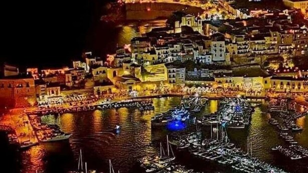 A nighttime view of a densely packed historic town with buildings along a waterfront, illuminated by artificial lighting. - Alcamo Marina Villa Pool (Alcamo)