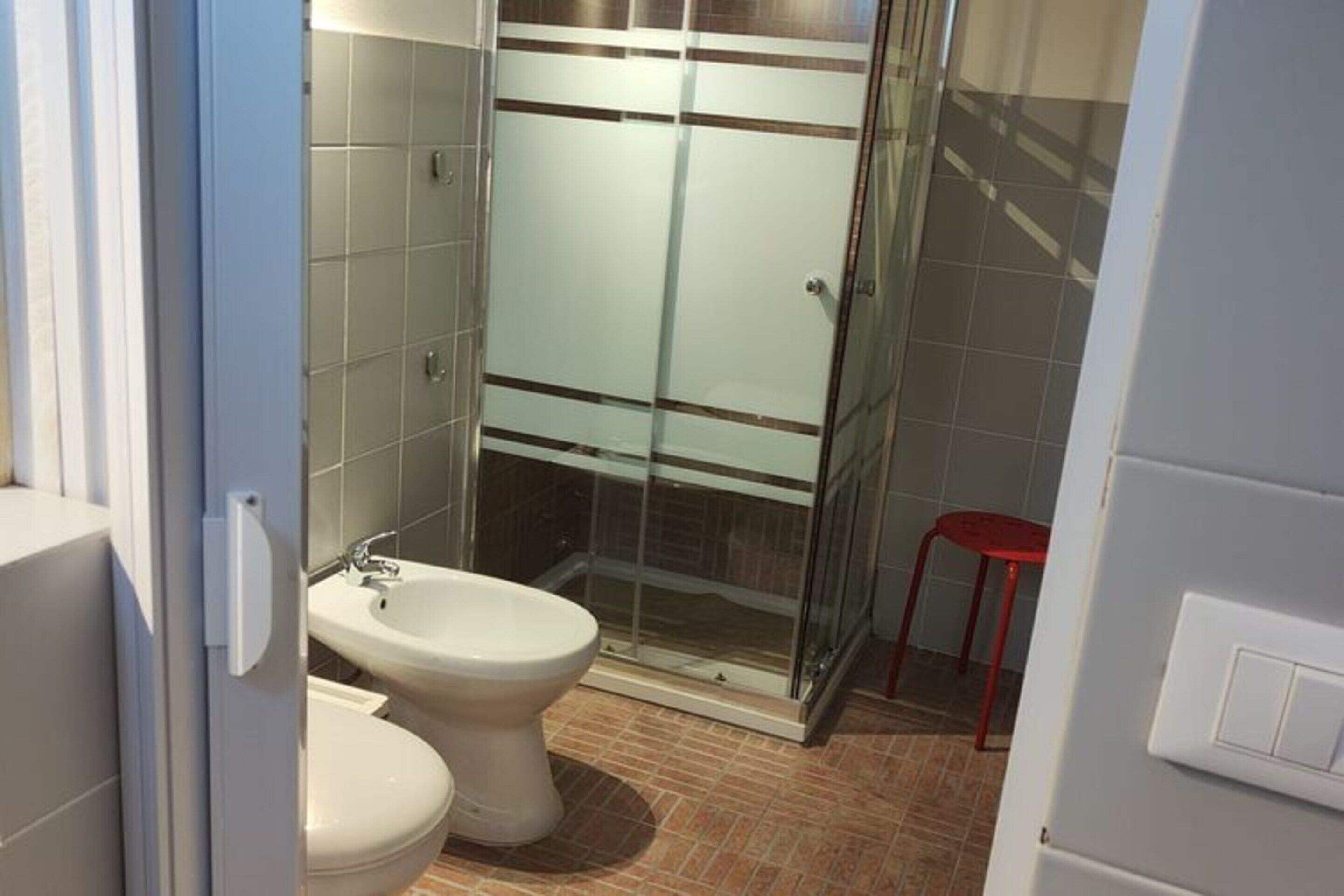 Een moderne badkamer met een douchecabine van glas, een wit toilet en een bidet.