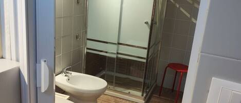 Een moderne badkamer met een douchecabine van glas, een wit toilet en een bidet.