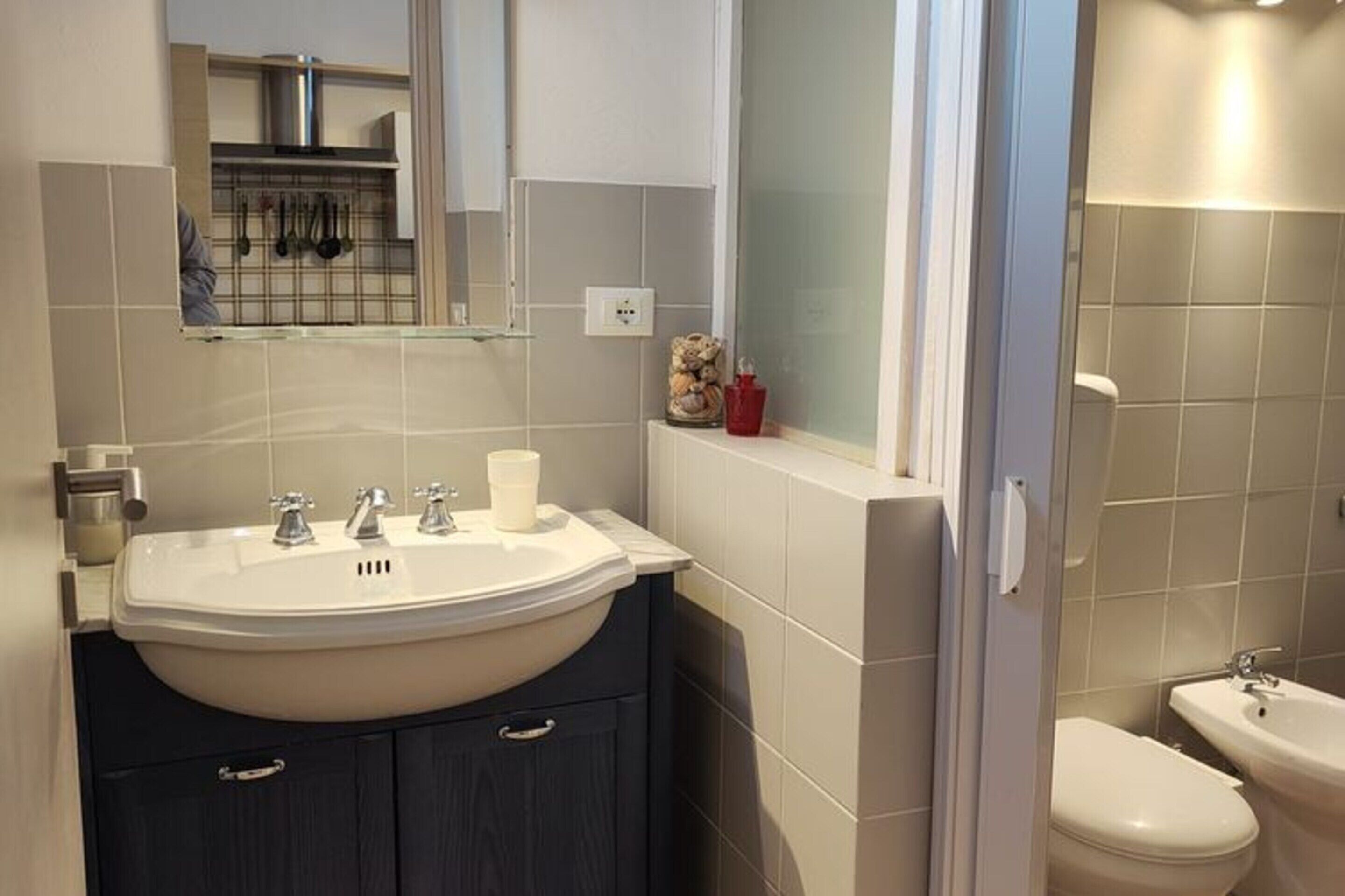 A modern bathroom with a large sink, a mirror, and a toilet.