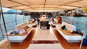 A boat with a covered deck, seating areas, and a central table with a basket. - Alcamo Marina Villa Pool (Alcamo)