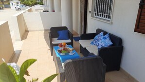 A patio with wicker furniture, a blue table, and a fruit platter. - Belvilla by Oyo Holiday Home in Ispica (Ispica)