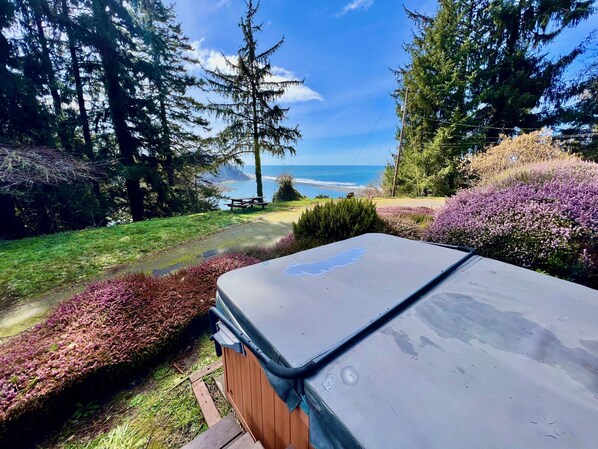 A hot tub in a garden with a view of the ocean and trees.