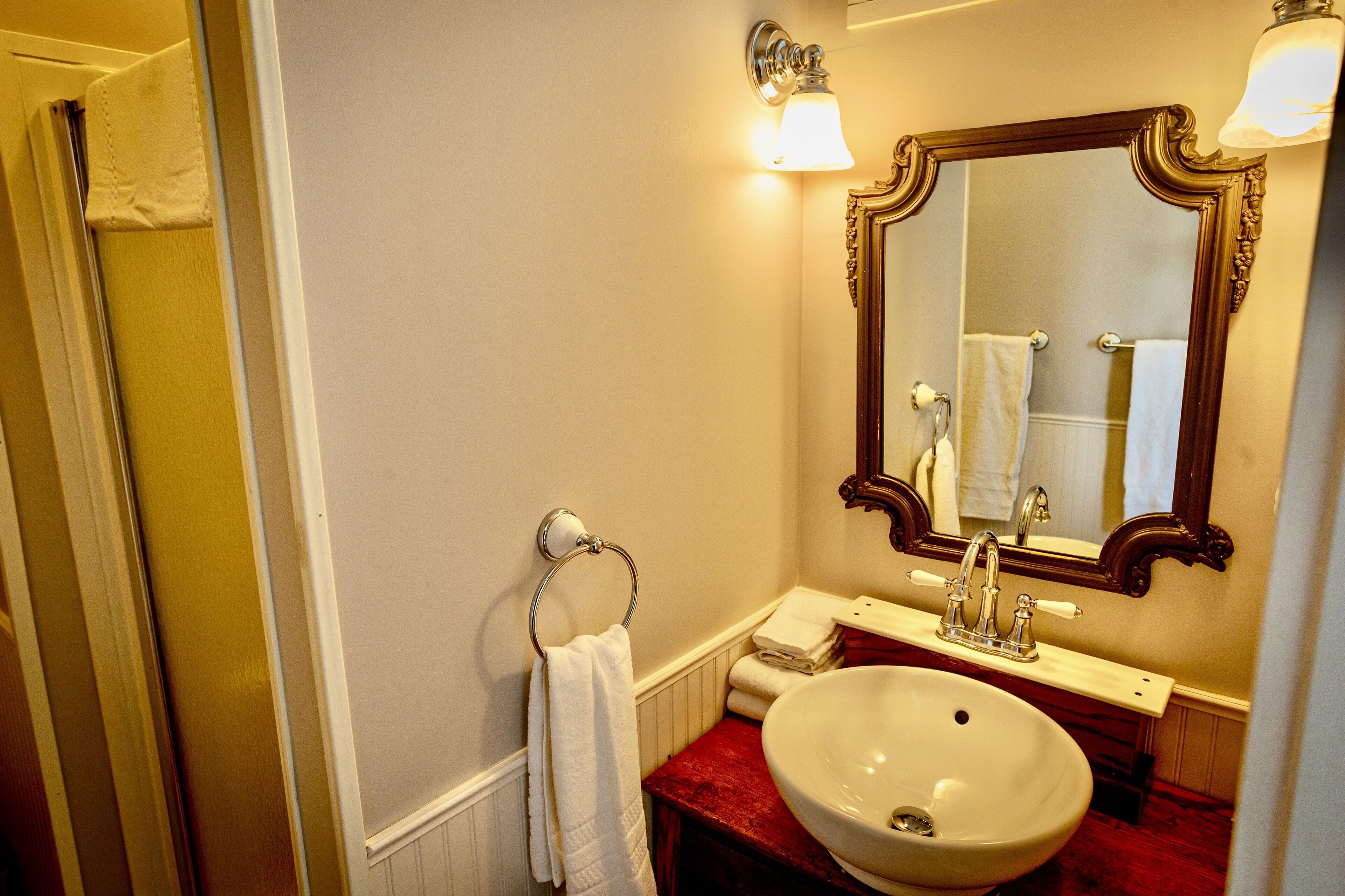 A bathroom with a white sink, a mirror with a wooden frame, and a red countertop.
