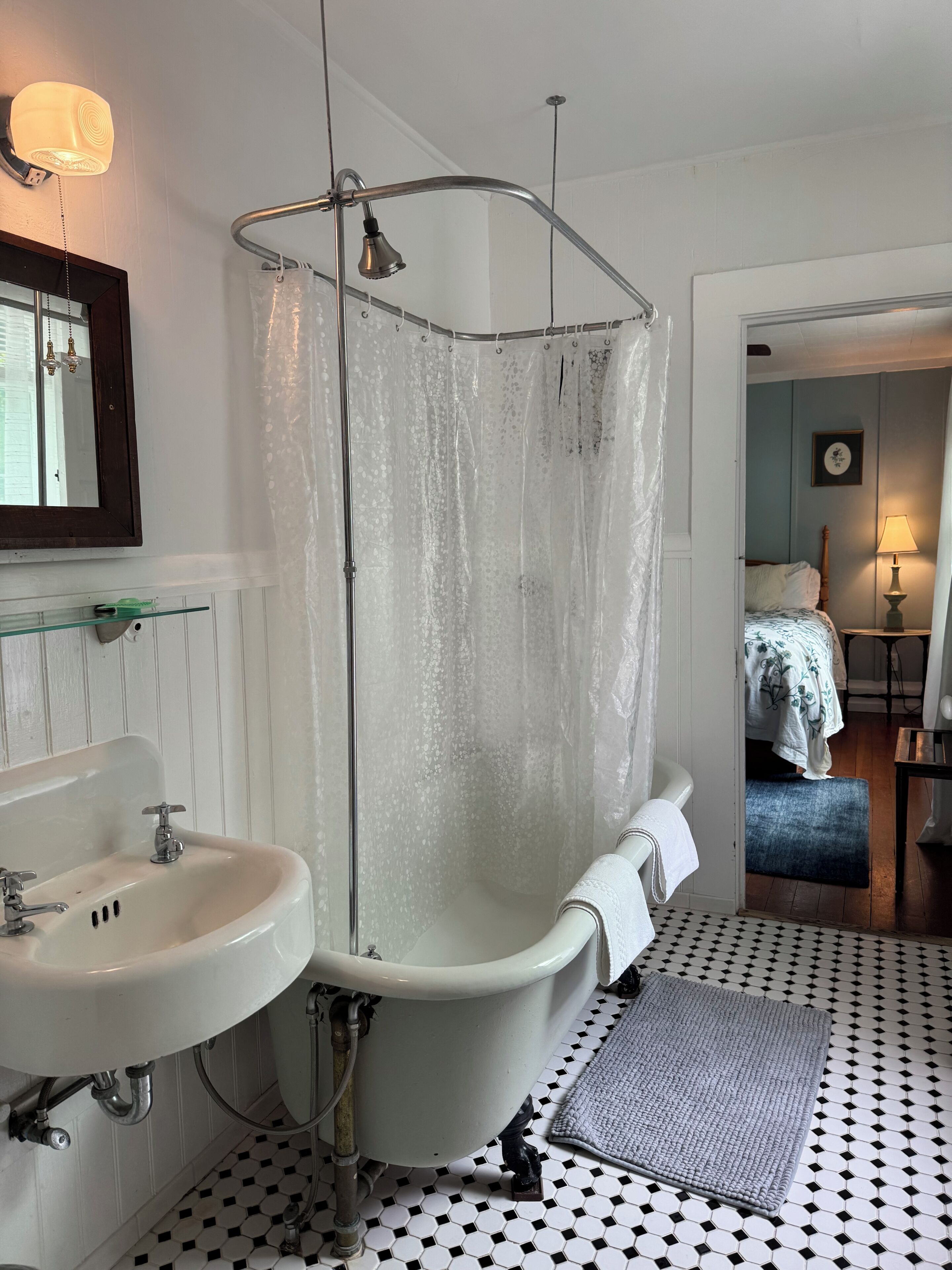 A bathroom with a white bathtub, a glass-enclosed shower, a white sink, and a mirror.