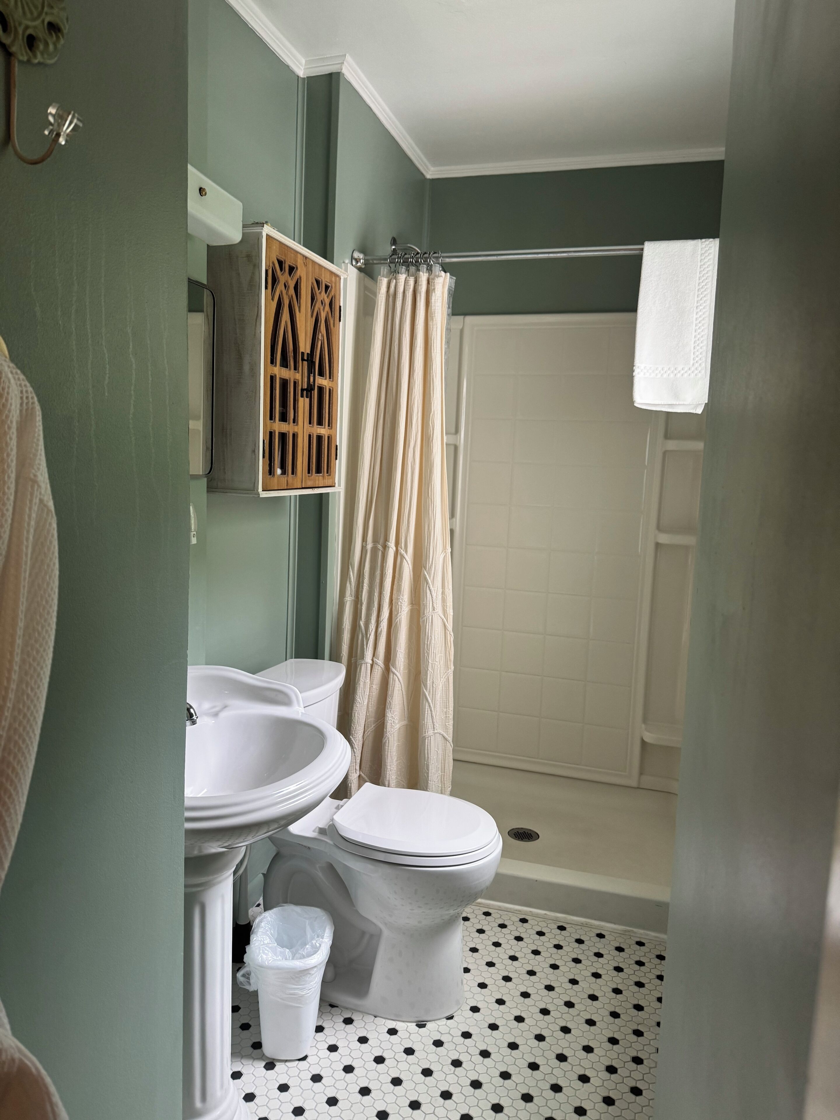 Un baño con inodoro, bidé y lavabo, ducha con cortina y suelo de baldosas.