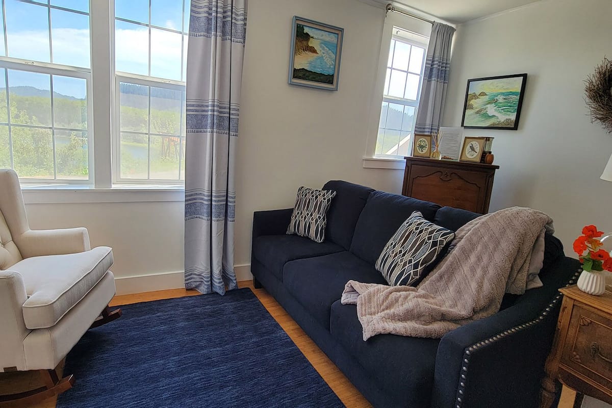 A living room with a white armchair, a dark blue sofa, and a wooden cabinet.