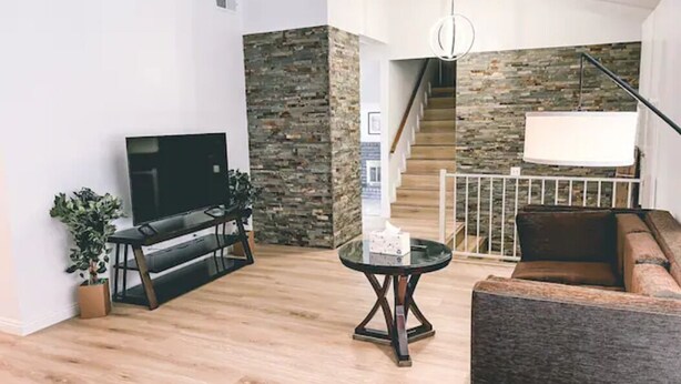 Een moderne woonkamer met een flatscreen televisie, een ronde salontafel en een bank.