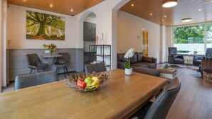 A spacious dining area with a wooden table, chairs, and a fruit bowl. There is a sofa and a coffee table in the background. - Stay With Garden, Limburg (Kerkrade)